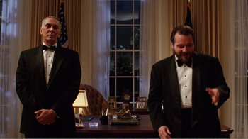 Movie still from “Dave” (1993), directed by Ivan Reitman – Two men in tuxedos standing in front of a desk; Medium shot, Low angle