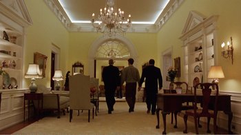 Movie still from “Dave” (1993), directed by Ivan Reitman – Three men are walking through a large room with a chandelier; Wide shot, Low angle