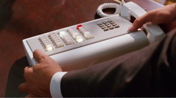 Movie still from “Dave” (1993), directed by Ivan Reitman – A person in a business suit is holding a remote control; Extreme Close Up shot, High angle