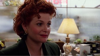 Movie still from “Dave” (1993), directed by Ivan Reitman – A person sitting at a table near a lamp; Close Up shot, Over the shoulder angle