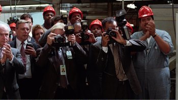 Movie still from “Dave” (1993), directed by Ivan Reitman – A group of people taking pictures with cameras; Medium shot, Low angle