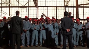 Movie still from “Dave” (1993), directed by Ivan Reitman – A group of men in blue overalls and red hard hats; Wide shot, Low angle