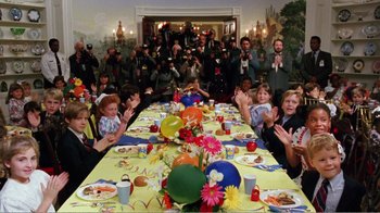 Movie still from “Dave” (1993), directed by Ivan Reitman – A group of people sitting at a table with food; Wide shot, High angle