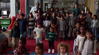 Movie still from “Dave” (1993), directed by Ivan Reitman – A large group of children standing in front of a man; Wide shot, High angle