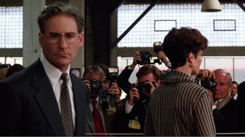 Movie still from “Dave” (1993), directed by Ivan Reitman – A group of people taking pictures of a man in a suit; Medium shot, Over the shoulder angle
