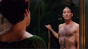 Movie still from “Dave” (1993), directed by Ivan Reitman – A man in a fur coat is looking at himself in the mirror; Medium shot, Over the shoulder angle