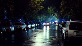 Movie still from “Dave” (1993), directed by Ivan Reitman – Cars are parked on the side of the road at night; Extreme Wide shot, High angle