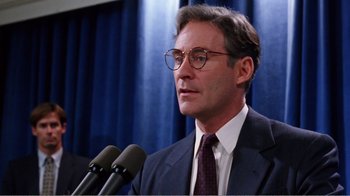 Movie still from “Dave” (1993), directed by Ivan Reitman – A man in a suit and tie speaking at a microphone; Close Up shot, Low angle