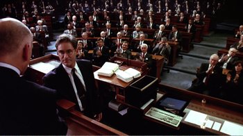 Movie still from “Dave” (1993), directed by Ivan Reitman – A man standing in front of a group of people; Wide shot, High angle