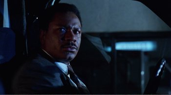 Movie still from “Dave” (1993), directed by Ivan Reitman – A man in a suit sitting in a car at night; Close Up shot, Low angle