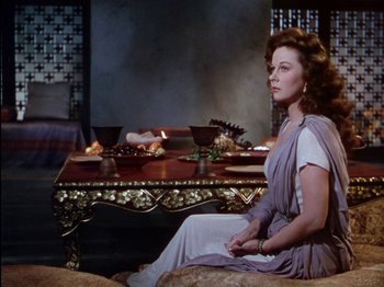 Movie still from “David and Bathsheba” (1951), directed by Henry King – A woman sitting in front of a table with food on top of it; Medium shot, Over the shoulder angle