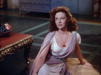 Movie still from “David and Bathsheba” (1951), directed by Henry King – A woman sitting on top of a chair wearing a dress; Medium shot, High angle