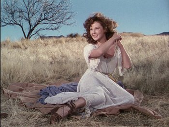 Movie still from “David and Bathsheba” (1951), directed by Henry King – A woman sitting on a blanket in a field; Wide shot, Low angle