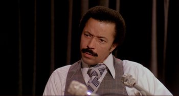 Movie still from “Dawn of the Dead” (1978), directed by George A. Romero – A man in a tie and a plaid vest looks to his left; Close Up shot, High angle