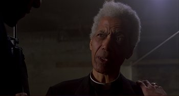 Movie still from “Dawn of the Dead” (1978), directed by George A. Romero – An older man wearing a priest's outfit and white hair; Close Up shot, Low angle