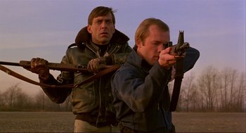 Movie still from “Dawn of the Dead” (1978), directed by George A. Romero – Two men are holding guns in a field; Medium shot, Low angle