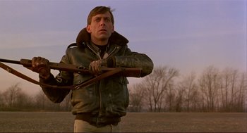 Movie still from “Dawn of the Dead” (1978), directed by George A. Romero – A man in a leather jacket holding two guns; Close Up shot, Low angle