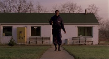 Movie still from “Dawn of the Dead” (1978), directed by George A. Romero – A man walking down a sidewalk holding a black cat; Wide shot, Low angle