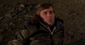 Movie still from “Dawn of the Dead” (1978), directed by George A. Romero – A man in a leather jacket is laying on the ground; Close Up shot, Overhead angle