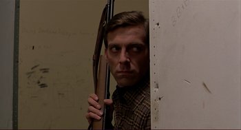 Movie still from “Dawn of the Dead” (1978), directed by George A. Romero – A man holding a rifle behind a wall; Close Up shot, Low angle