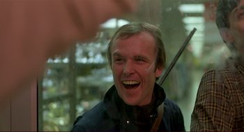 Movie still from “Dawn of the Dead” (1978), directed by George A. Romero – A person laughing with a person holding a stick; Close Up shot, Over the shoulder angle