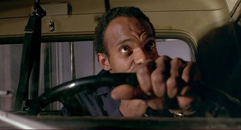 Movie still from “Dawn of the Dead” (1978), directed by George A. Romero – A man holding the steering wheel of a car; Close Up shot, Low angle