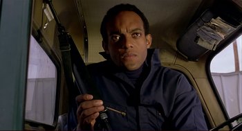 Movie still from “Dawn of the Dead” (1978), directed by George A. Romero – A man holding an umbrella while sitting in a vehicle; Close Up shot, Low angle