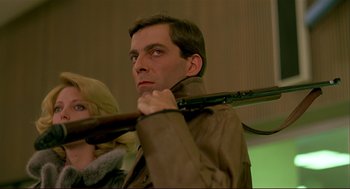 Movie still from “Dawn of the Dead” (1978), directed by George A. Romero – A man holding a rifle in front of a woman; Close Up shot, Low angle