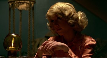 Movie still from “Dawn of the Dead” (1978), directed by George A. Romero – A woman with blonde hair sitting at a table with her hands crossed; Close Up shot, Over the shoulder angle