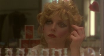 Movie still from “Dawn of the Dead” (1978), directed by George A. Romero – A woman with blonde curly hair is looking into a mirror; Close Up shot, Over the shoulder angle
