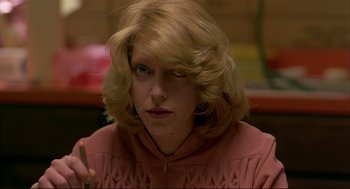 Movie still from “Dawn of the Dead” (1978), directed by George A. Romero – A woman with blonde hair is sitting at a table; Close Up shot, Over the shoulder angle