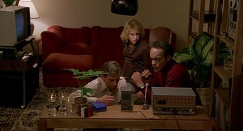 Movie still from “Dawn of the Dead” (1978), directed by George A. Romero – A group of people sitting at a table with electronics; Medium shot, High angle