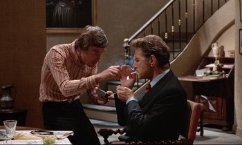 Movie still from “Day for Night” (1973), directed by François Truffaut – Two men in suits are sitting at a dinner table; Medium shot, Over the shoulder angle