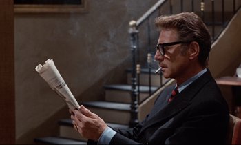 Movie still from “Day for Night” (1973), directed by François Truffaut – A man in a suit reading a newspaper; Close Up shot, Over the shoulder angle