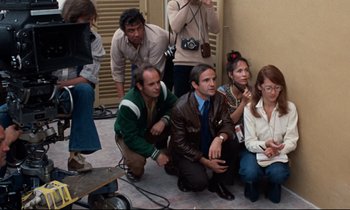 Movie still from “Day for Night” (1973), directed by François Truffaut – A group of people sitting on the ground; Medium shot, High angle