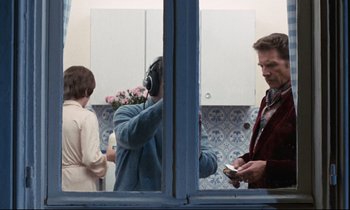 Movie still from “Day for Night” (1973), directed by François Truffaut – A man holding a bouquet of flowers in front of two other people; Medium shot, Over the shoulder angle