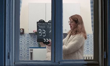 Movie still from “Day for Night” (1973), directed by François Truffaut – A woman is holding up a clapperboard in front of a mirror; Medium shot, Over the shoulder angle