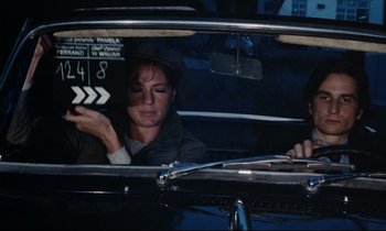 Movie still from “Day for Night” (1973), directed by François Truffaut – A woman sitting in the back seat of a car; Medium shot, High angle