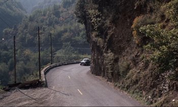 Movie still from “Day for Night” (1973), directed by François Truffaut – A car driving down a curvy road on a mountain side; Extreme Wide shot, High angle