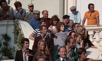 Movie still from “Day for Night” (1973), directed by François Truffaut – A group of people standing around each other on a porch; Wide shot, High angle