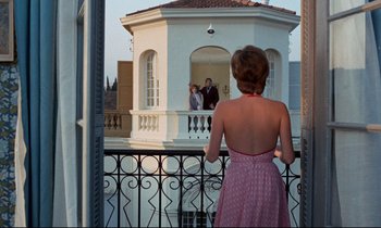 Movie still from “Day for Night” (1973), directed by François Truffaut – A woman standing on a balcony looking at two people; Wide shot, Low angle