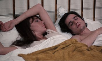 Movie still from “Day for Night” (1973), directed by François Truffaut – A man and a woman laying in a bed together; Medium shot, High angle