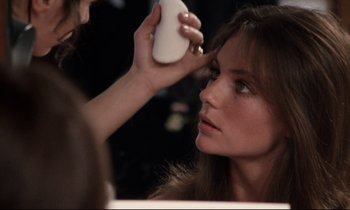Movie still from “Day for Night” (1973), directed by François Truffaut – A woman putting makeup on her face in a mirror; Close Up shot, Over the shoulder angle