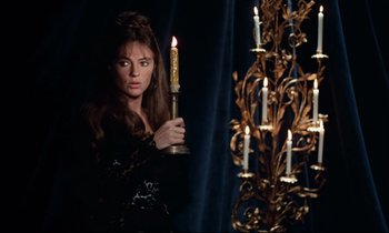 Movie still from “Day for Night” (1973), directed by François Truffaut – A woman holding a candle in front of a chandelier; Medium shot, Over the shoulder angle