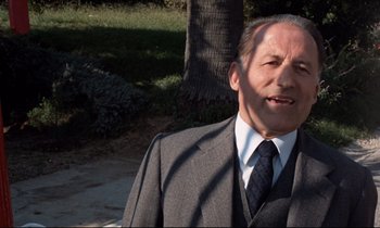 Movie still from “Day for Night” (1973), directed by François Truffaut – An older man wearing a suit and tie; Close Up shot, Low angle