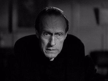 Black and white photograph of a man in a priest's outfit