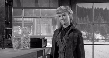 Movie still from “Day of the Outlaw” (1959), directed by André De Toth – A black and white photo of a woman standing in front of an oven; Medium shot, Low angle
