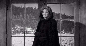 Movie still from “Day of the Outlaw” (1959), directed by André De Toth – A black and white photo of a woman standing in front of a window; Medium shot, Over the shoulder angle