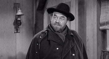 Movie still from “Day of the Outlaw” (1959), directed by André De Toth – An old photo of a man in a black hat and coat; Close Up shot, Over the shoulder angle
