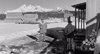 Movie still from “Day of the Outlaw” (1959), directed by André De Toth – A man in a coat and hat standing next to a man in a hat; Wide shot, Low angle